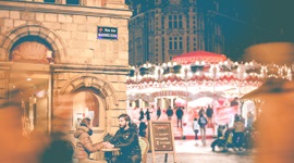 Two people sitting at an outdoor table next to a carnival.